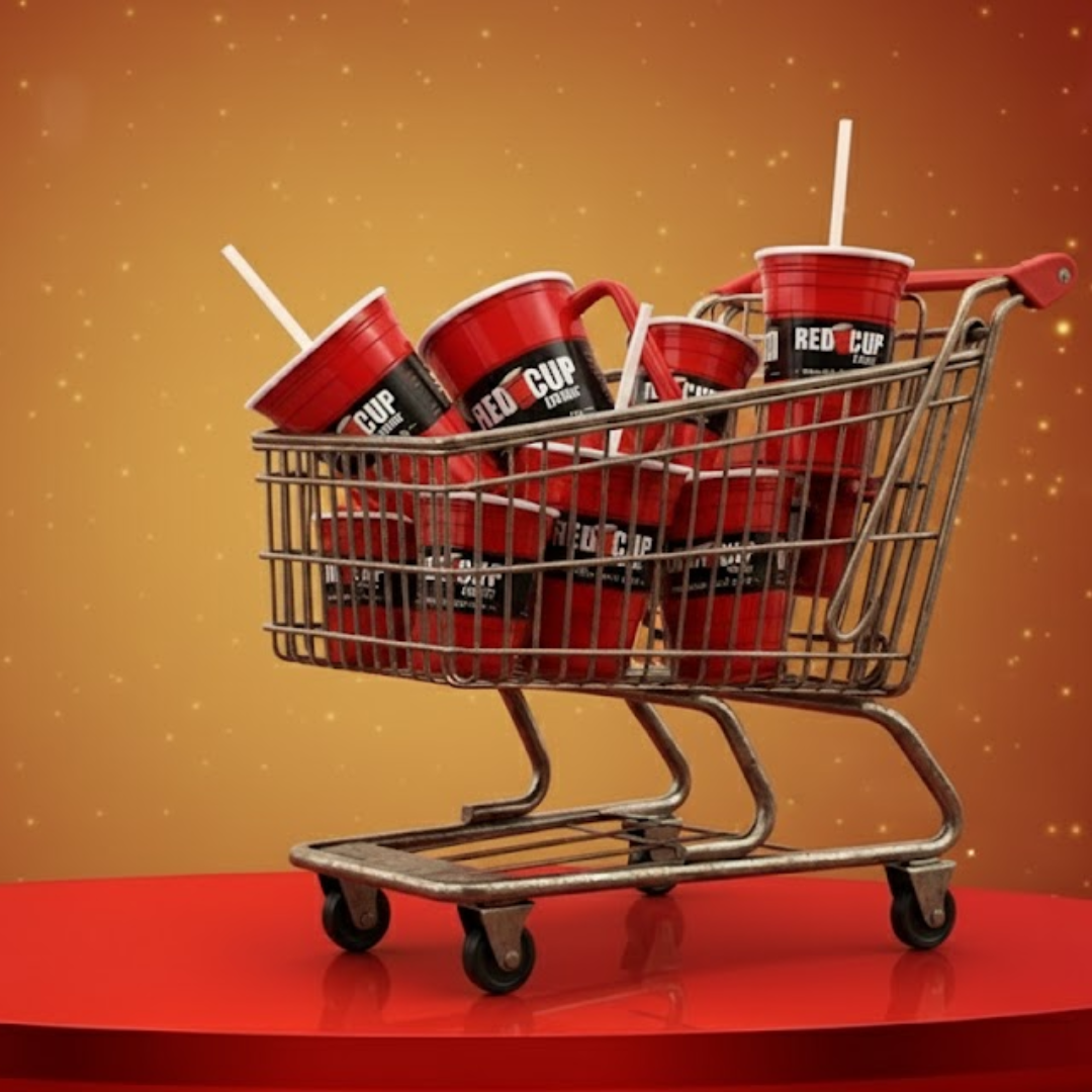 Miniature shopping cart filled with red plastic cups with straws, set against a sparkling orange background.